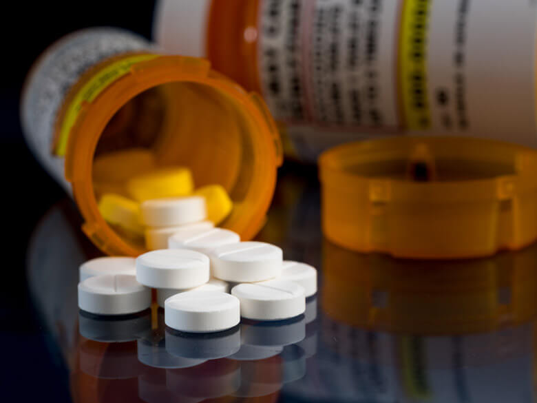 prescription tablets on table next to tipped over bottle